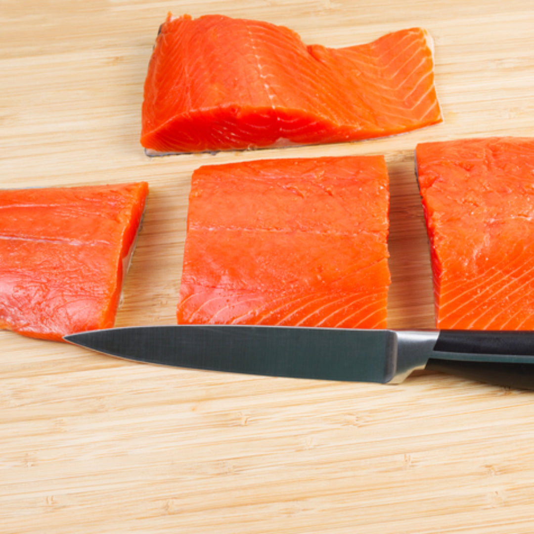 Fresh wild-caught red salmon (sockeye) fillet on a cutting board showing the deep red-orange flesh characteristic of sockeye salmon