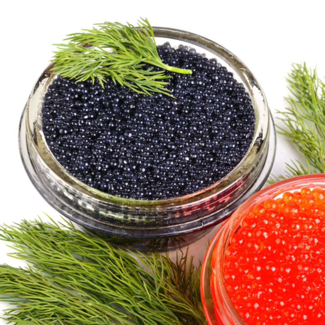 Golden-brown Ossetra sturgeon caviar pearls served in a mother-of-pearl spoon alongside blinis and crème fraîche on an elegant dark slate board