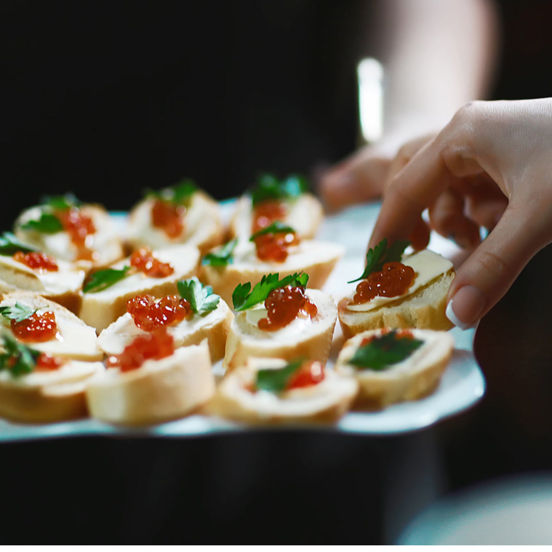 A plate of red caviar canapés with slices of cucumber and dill on a white plate.