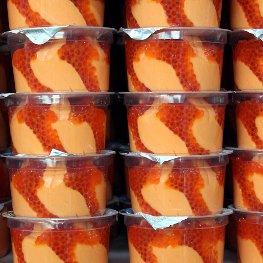 Close-up of freshly stored salmon red caviar in a glass jar, showcasing its vibrant color and pristine texture, set against a cool, refrigerated background