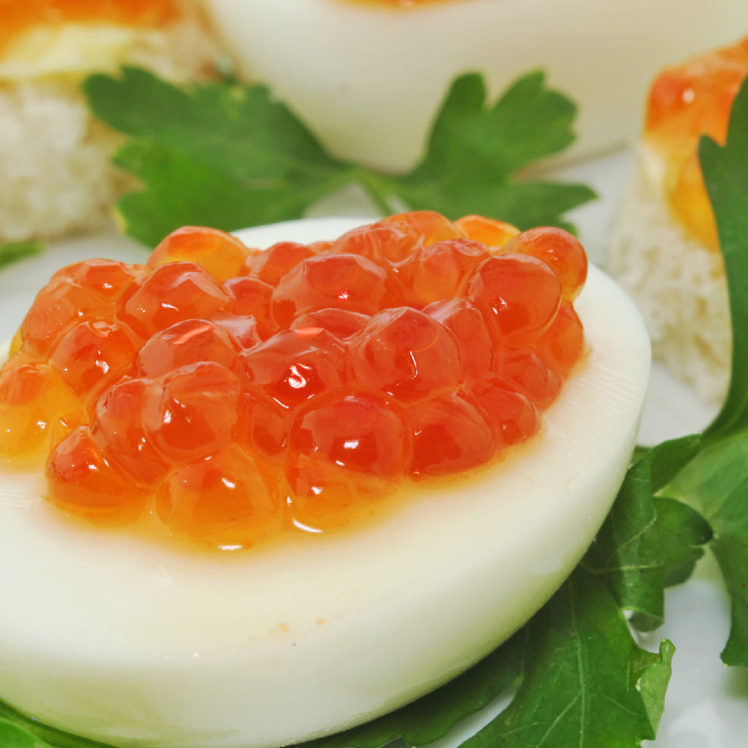 Creamy salmon roe spread on toast points garnished with fresh dill and chives, served on a wooden board with crackers and lemon wedges
