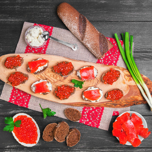 Salmon roe served on blinis with chilled vodka shots on a luxury dining table