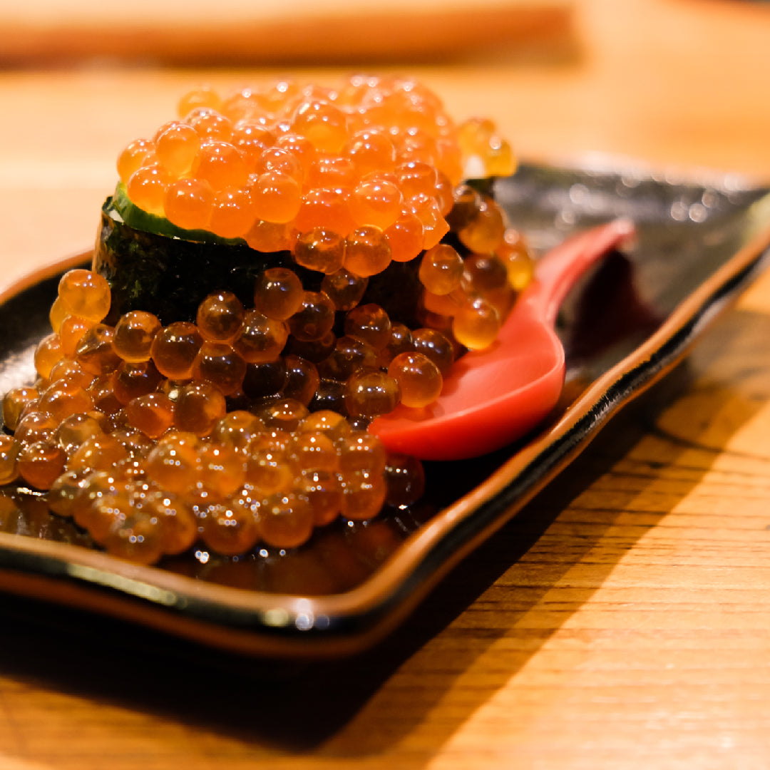 Salmon roe in an open jar with a spoon, stored on ice for freshness