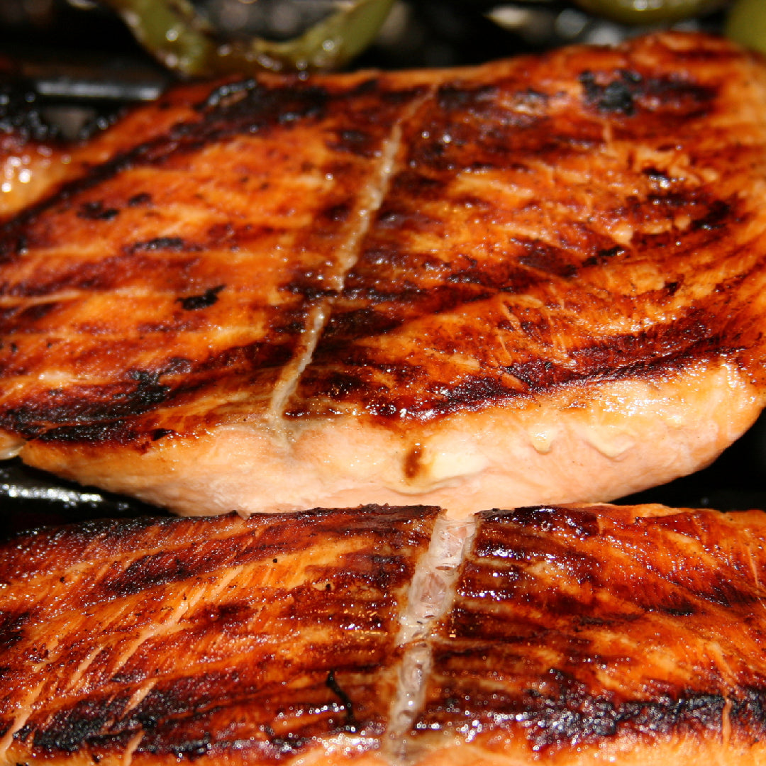 Grilled salmon fillet on a plate with asparagus and lemon wedges