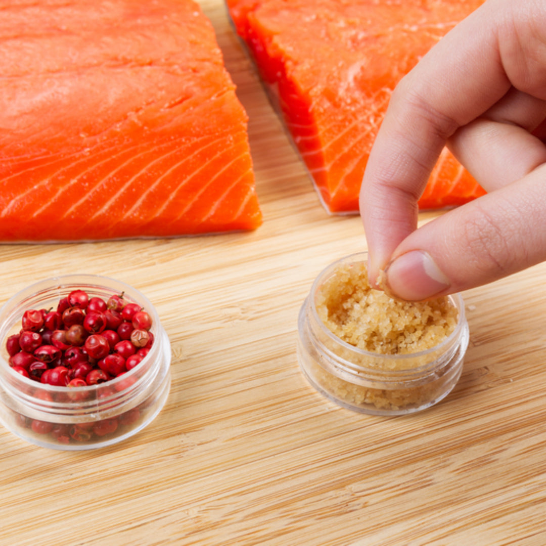 Silver salmon fillet seasoned with herbs, lemon slices, and spices on a wooden cutting board