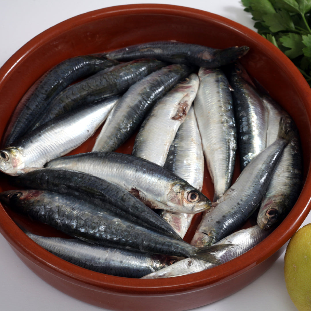 Portuguese sardine salad with mixed greens, cherry tomatoes, cucumber, black olives, and lemon dressing in a large bowl