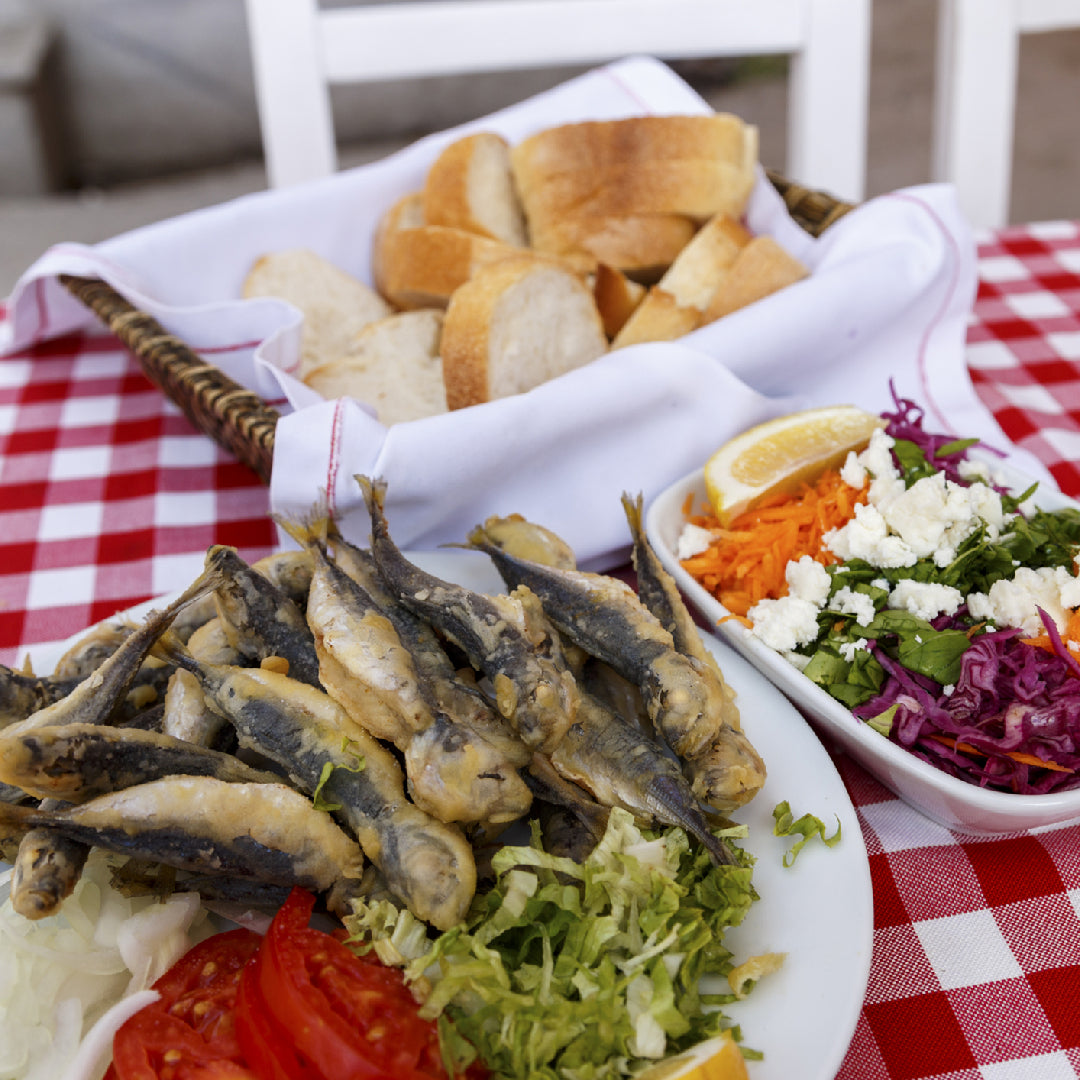 Hand-packed Portuguese sardines in olive oil served on a wooden board with lemon, herbs, and crusty bread