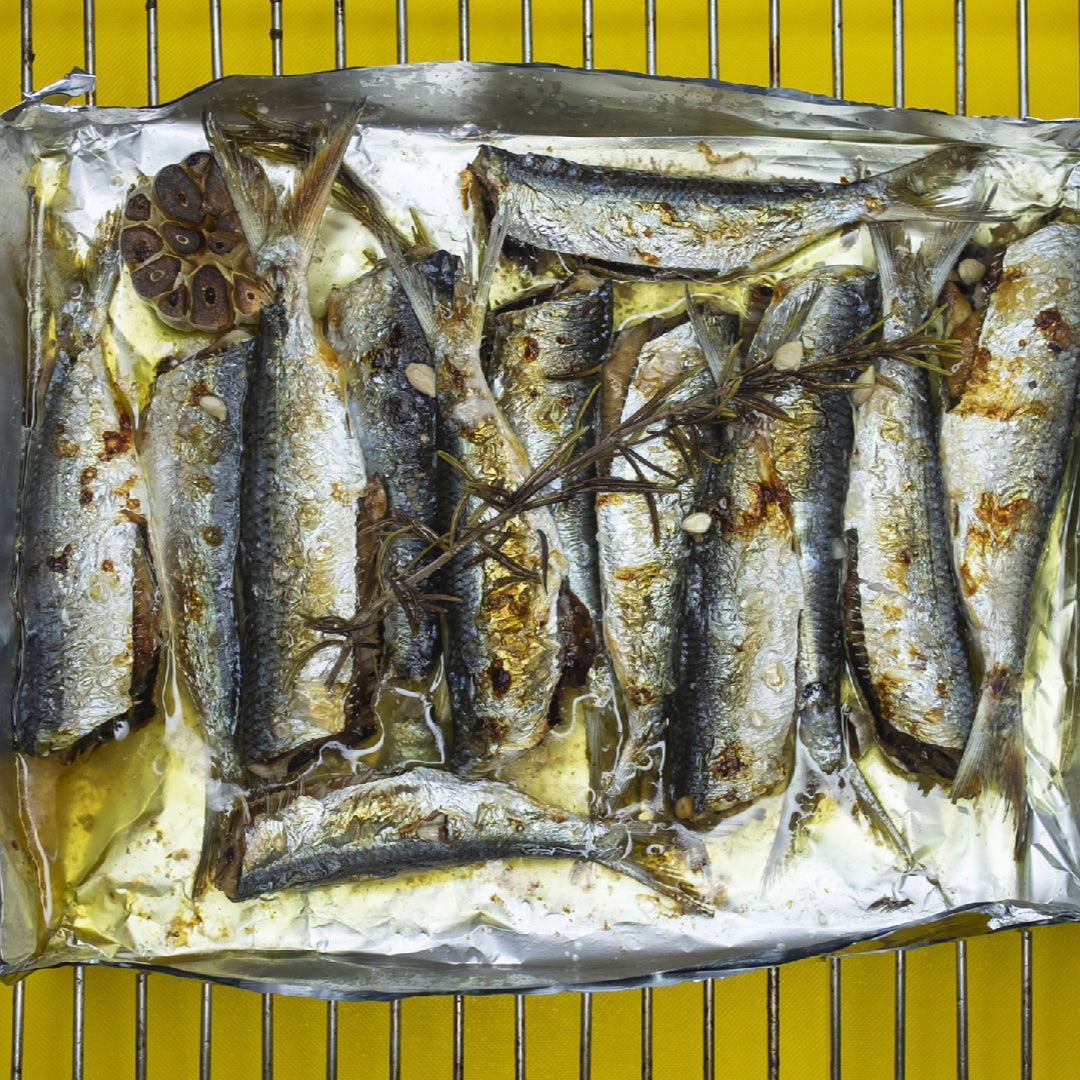 Creamy sardine dip in a white bowl garnished with fresh dill, capers, and a drizzle of olive oil served with crackers and vegetable crudités