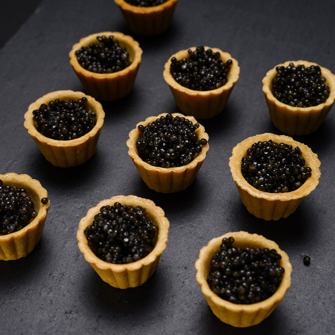 Sturgeon caviar arranged on a crystal dish with edible flowers and crushed ice for an expert fine dining presentation