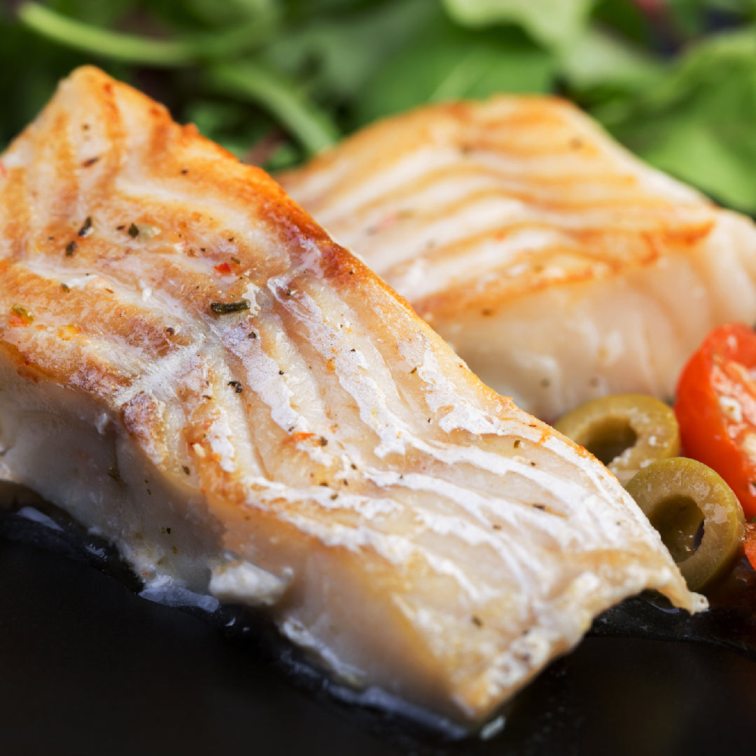 Sablefish fillet and seared tuna steak side by side on a white plate