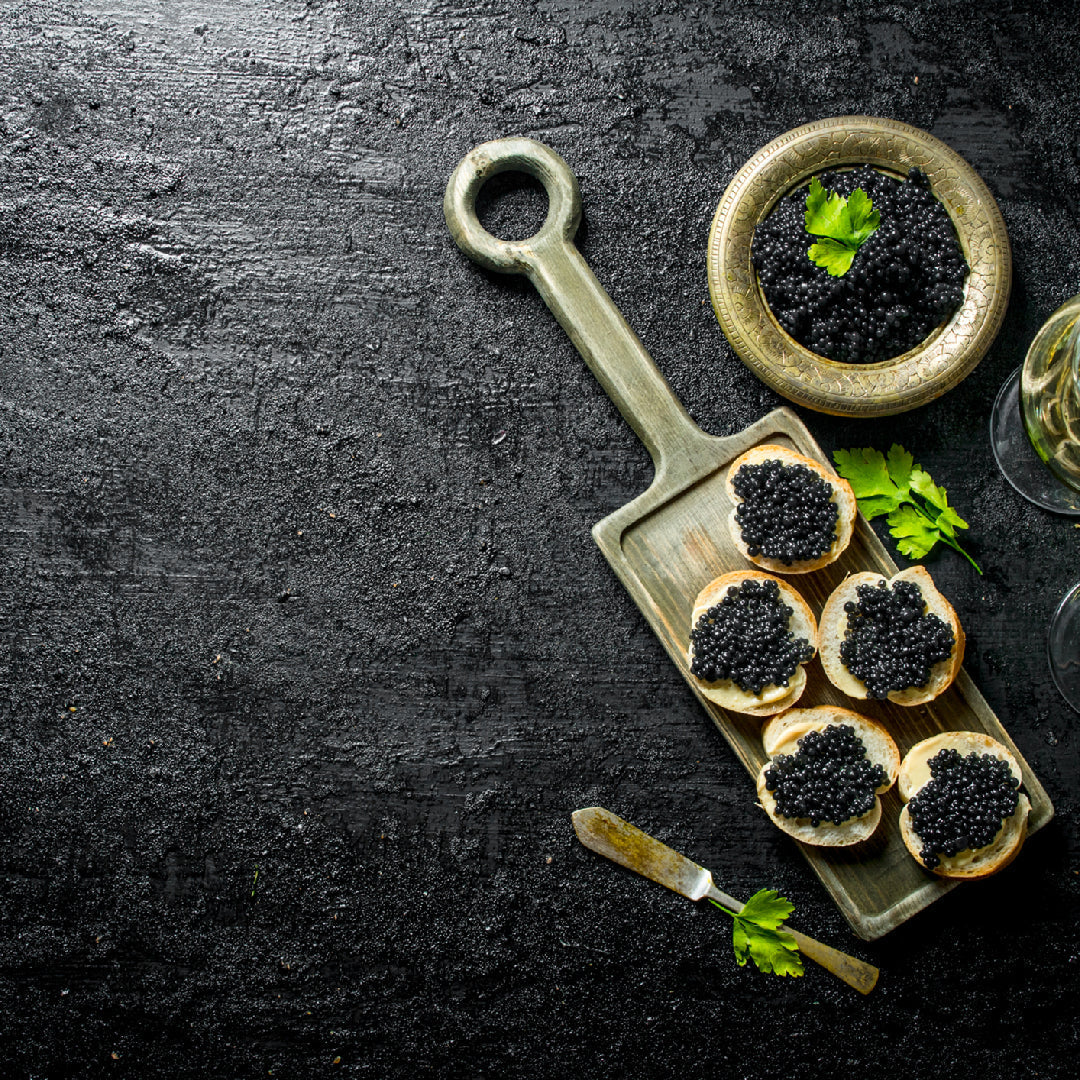 Assortment of premium sturgeon caviar varieties in tins on crushed ice with mother-of-pearl spoon