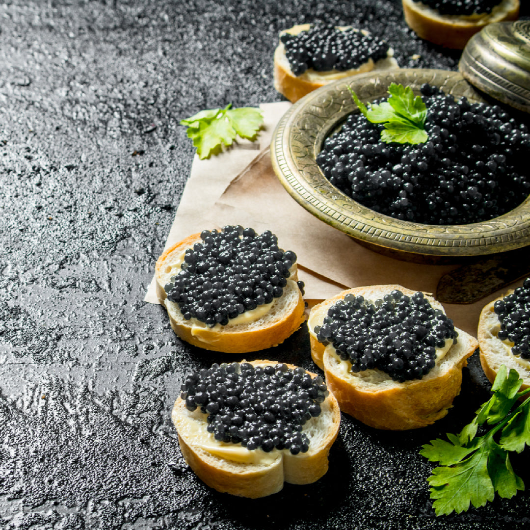 Premium sturgeon caviar tin served on crushed ice with blinis and crème fraîche for a dinner party