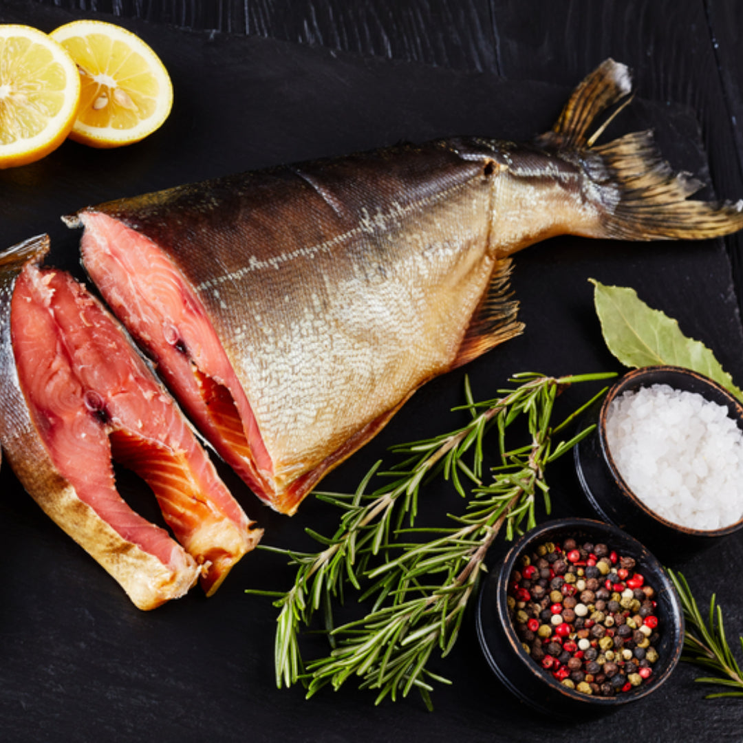 Thinly sliced cold smoked wild salmon on a wooden board with capers, red onion, cream cheese and fresh dill