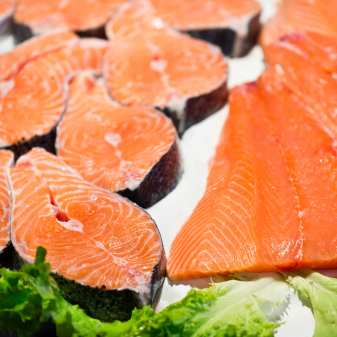 Side-by-side comparison of a salmon steak and salmon fillet on a wooden cutting board