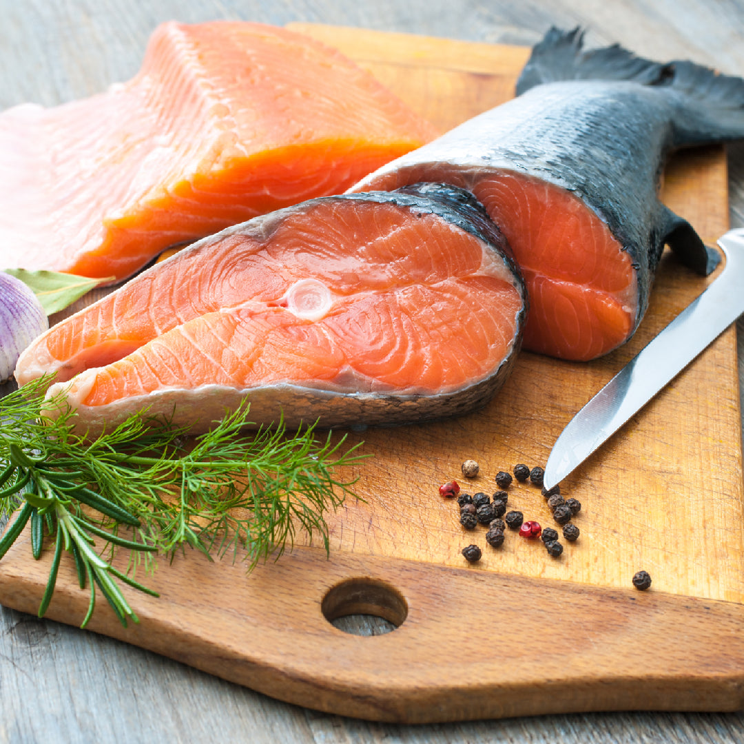 Fresh silver salmon fillet showing vibrant orange flesh on a cutting board