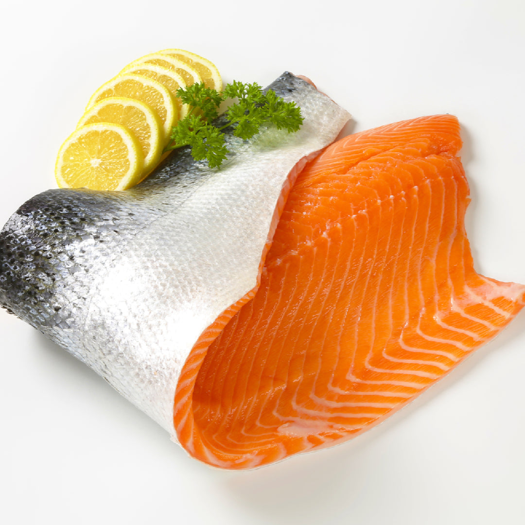 Grilled silver salmon fillet with lemon and dill garnish on a wooden cutting board