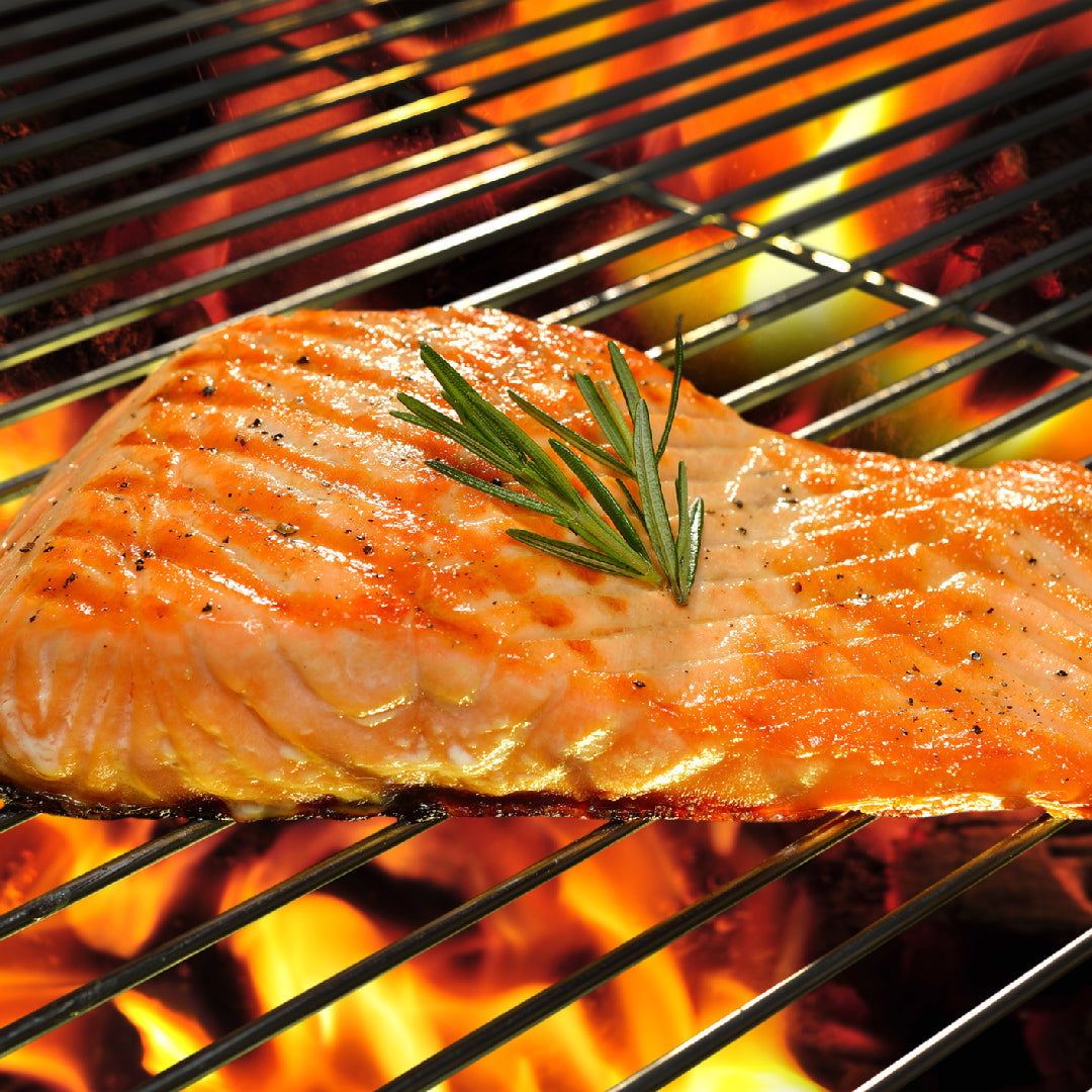 Pan-seared silver salmon fillet with a golden crust, lemon slices, fresh dill, and roasted vegetables on a plate
