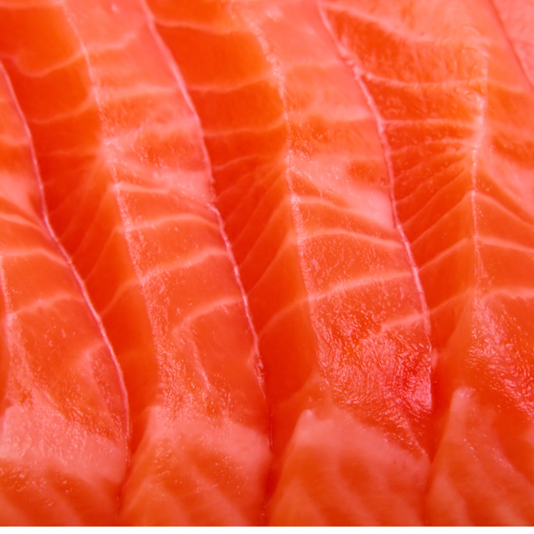 Fresh salmon fillet with lemon slices and herbs on a wooden board
