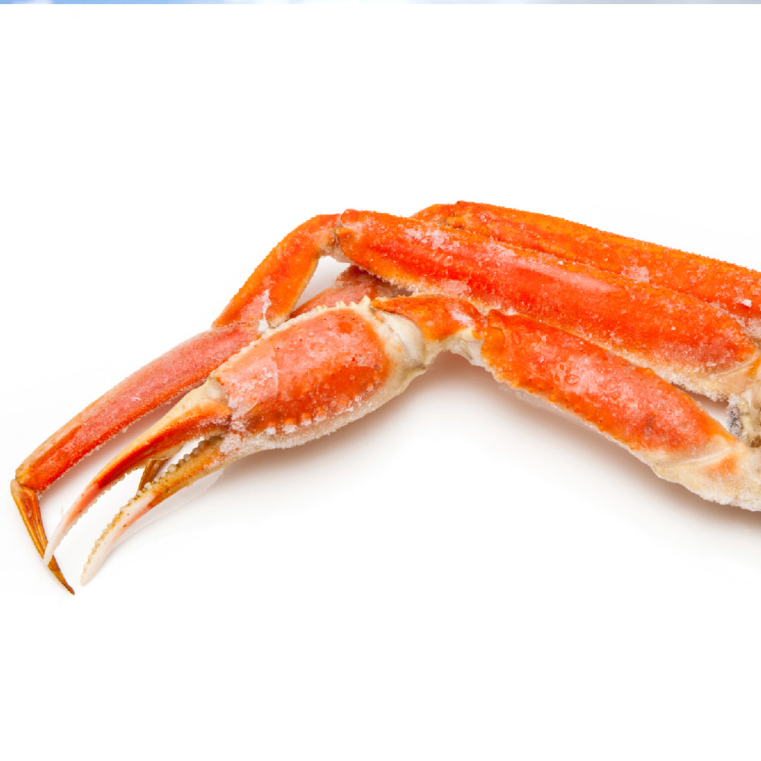 Snow crab legs arranged on a platter with homemade cocktail sauce, lemon wedges, and fresh parsley