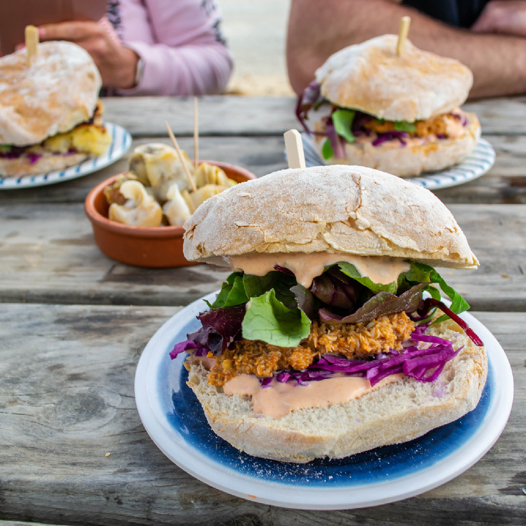 Dungeness crab sandwich on a toasted brioche bun with lemon aioli, fresh greens, and lemon wedge on a wooden board