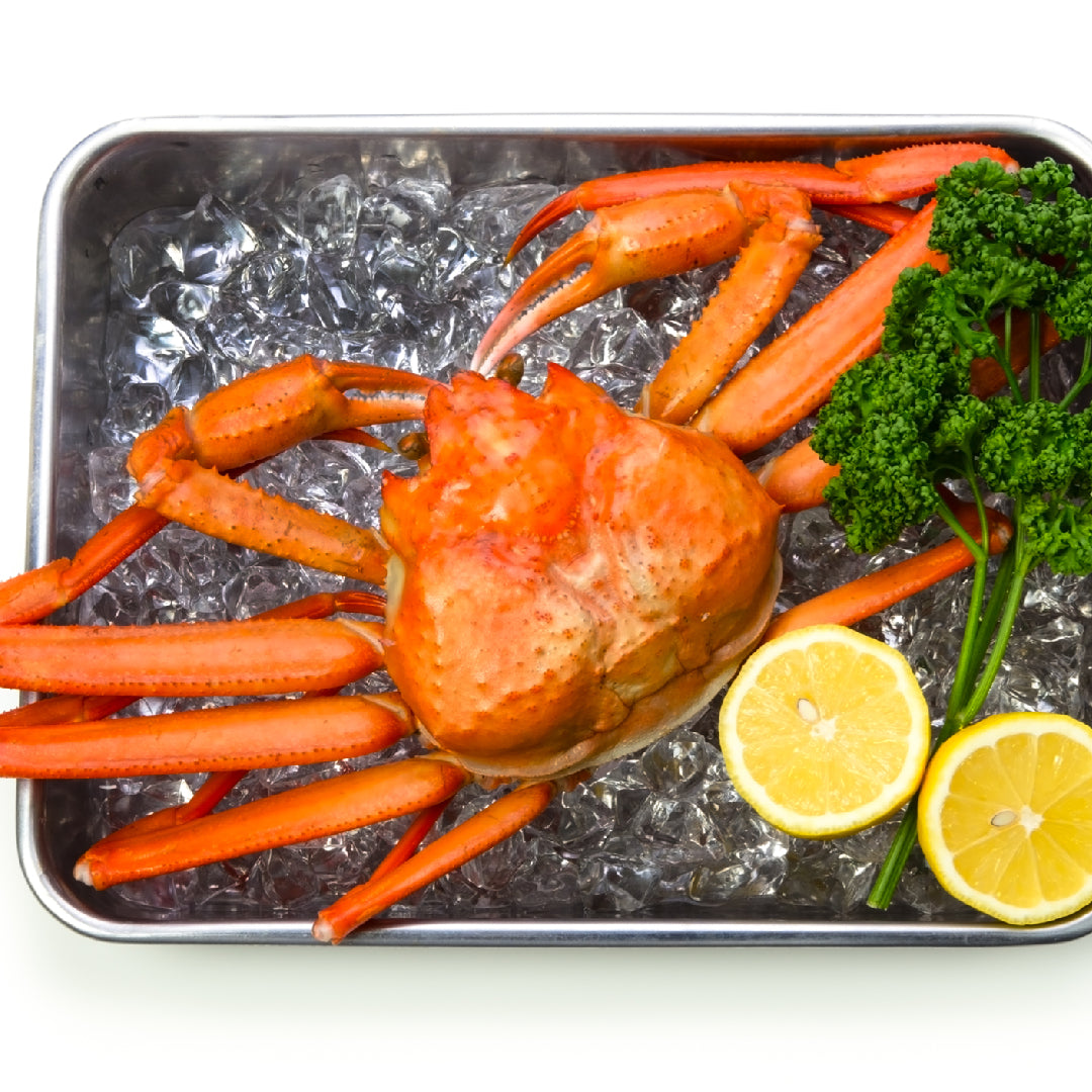 Steamed snow crab legs clusters served on a platter with melted garlic butter, lemon wedges, and fresh parsley