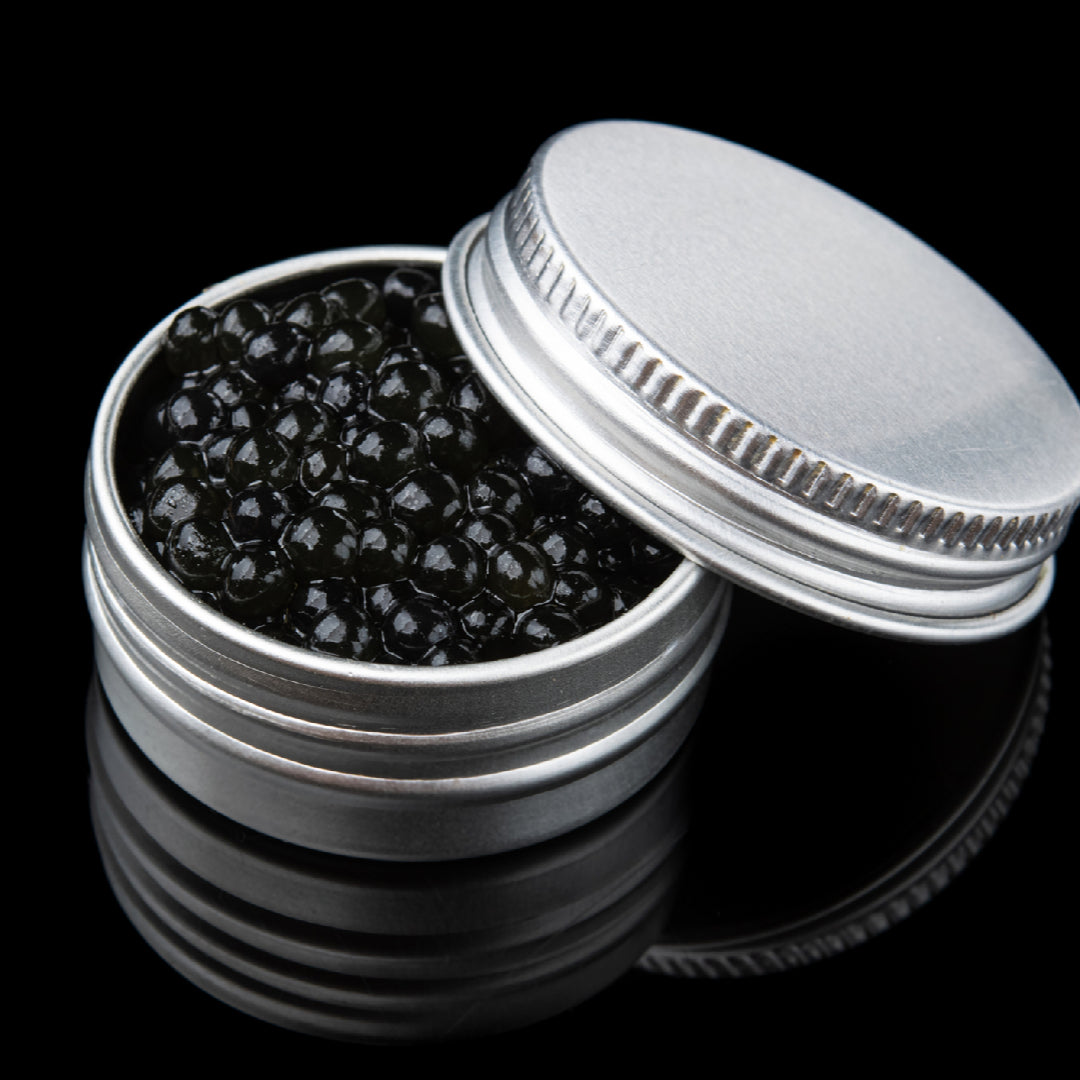 Assorted sturgeon caviar varieties in tins showing different colors from black to golden on a marble surface