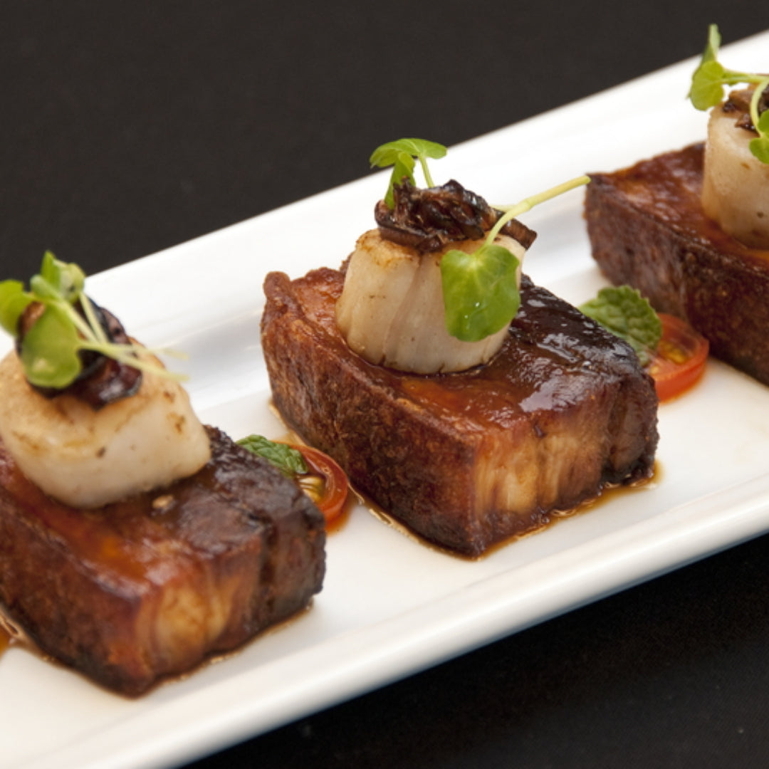 Bay scallops (small, sweet, tender) next to sea scallops (large, firm, meaty) — showing the dramatic size difference and the different textures that make each variety suited to completely different cooking methods