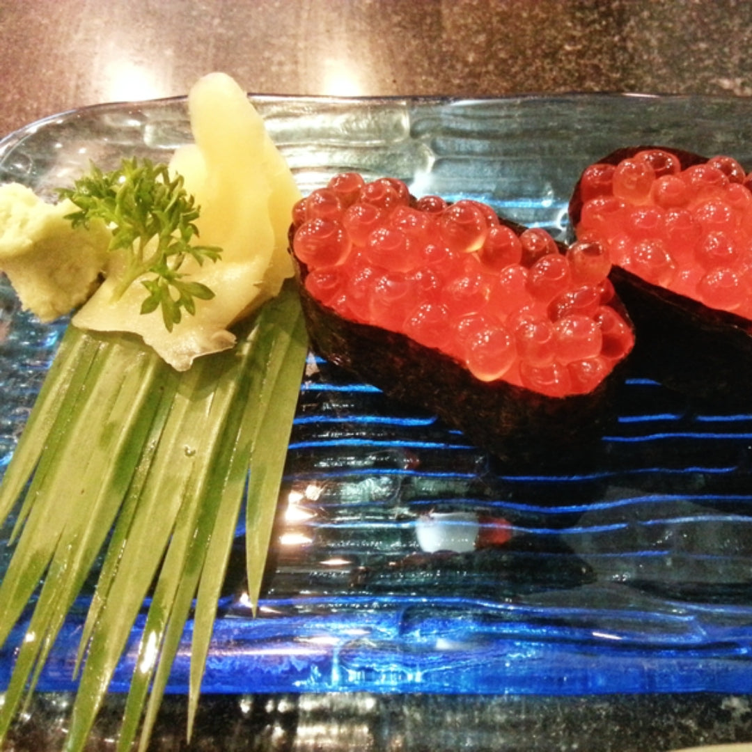 Assorted sushi rolls and nigiri on a wooden board with wasabi and ginger