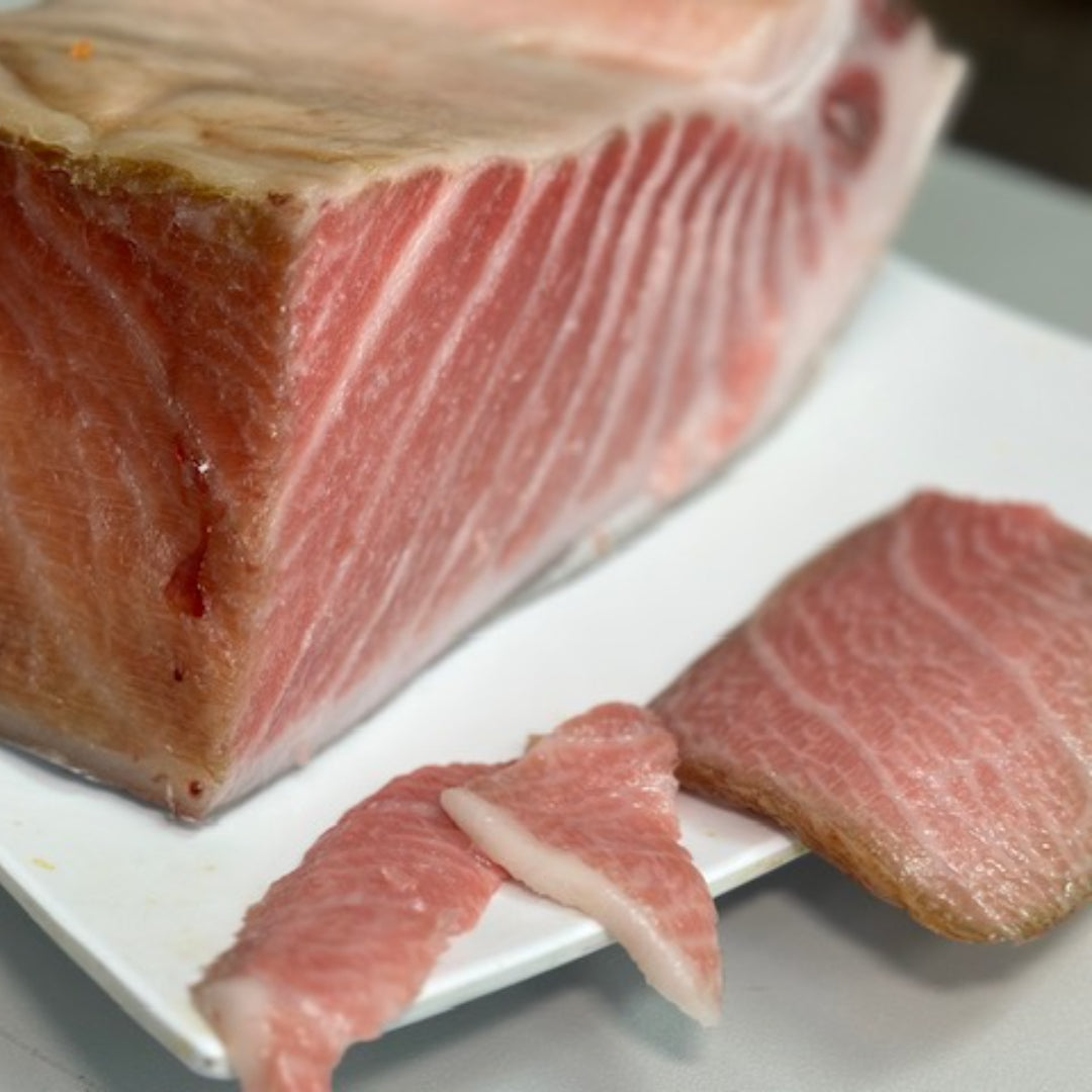 Sliced dry-aged Bluefin Tuna Belly Toro with deep ruby marbling on a wooden board with soy sauce and wasabi
