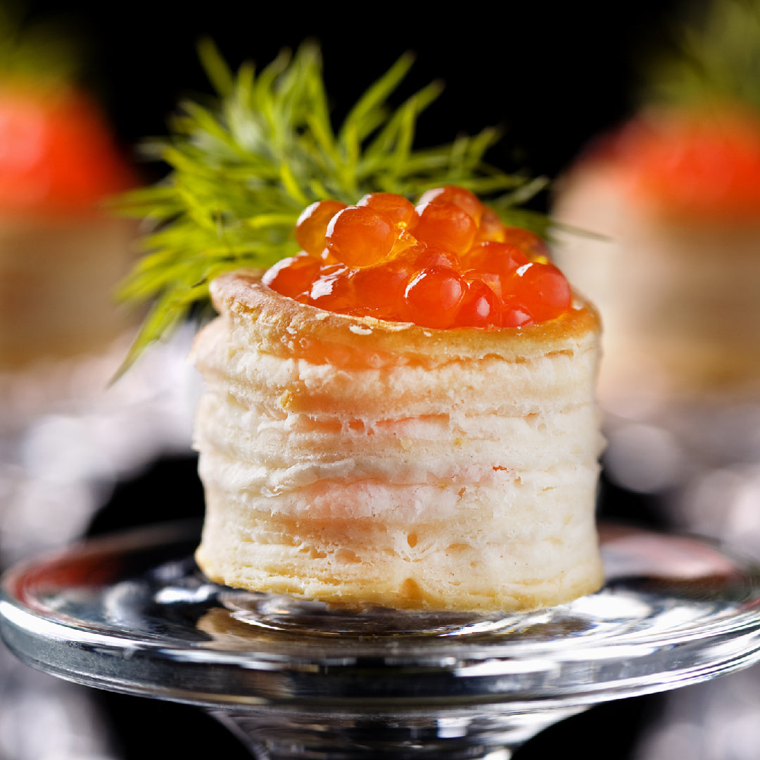 Fresh trout roe (trout caviar) served on blinis with crème fraîche and chives, showing the jewel-like orange eggs with a firm, popping texture