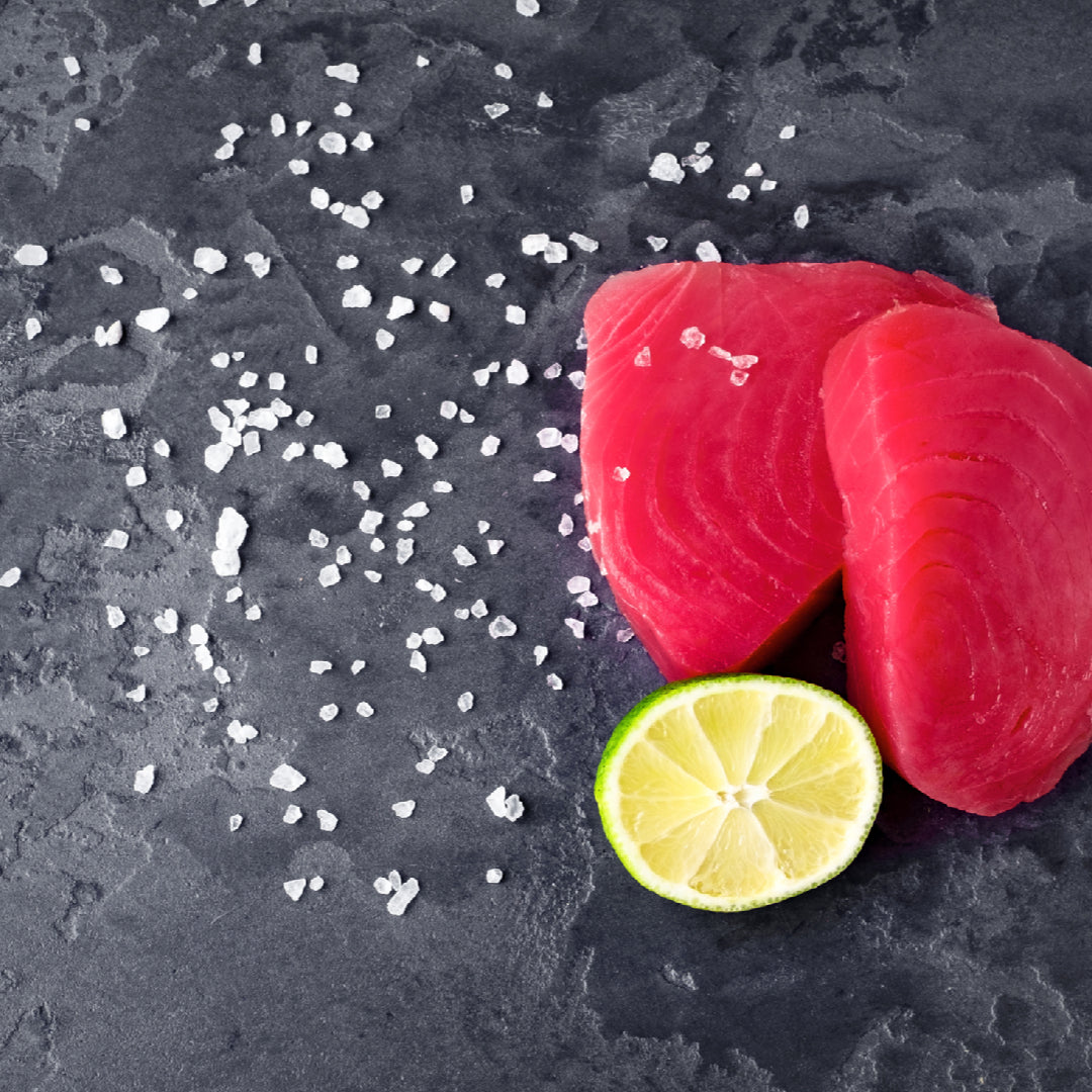 Thinly sliced sushi-grade Ahi tuna carpaccio on a chilled plate with capers, radishes, microgreens, and a drizzle of olive oil