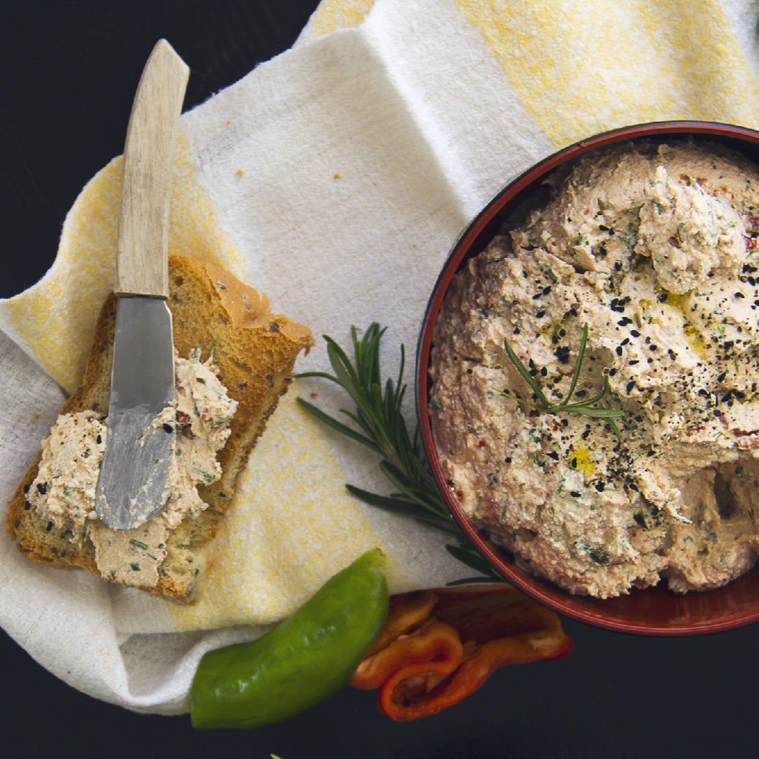 Bowl of creamy ahi tuna dip garnished with green onions, served with a side of crisp crackers and fresh vegetable sticks for dipping
