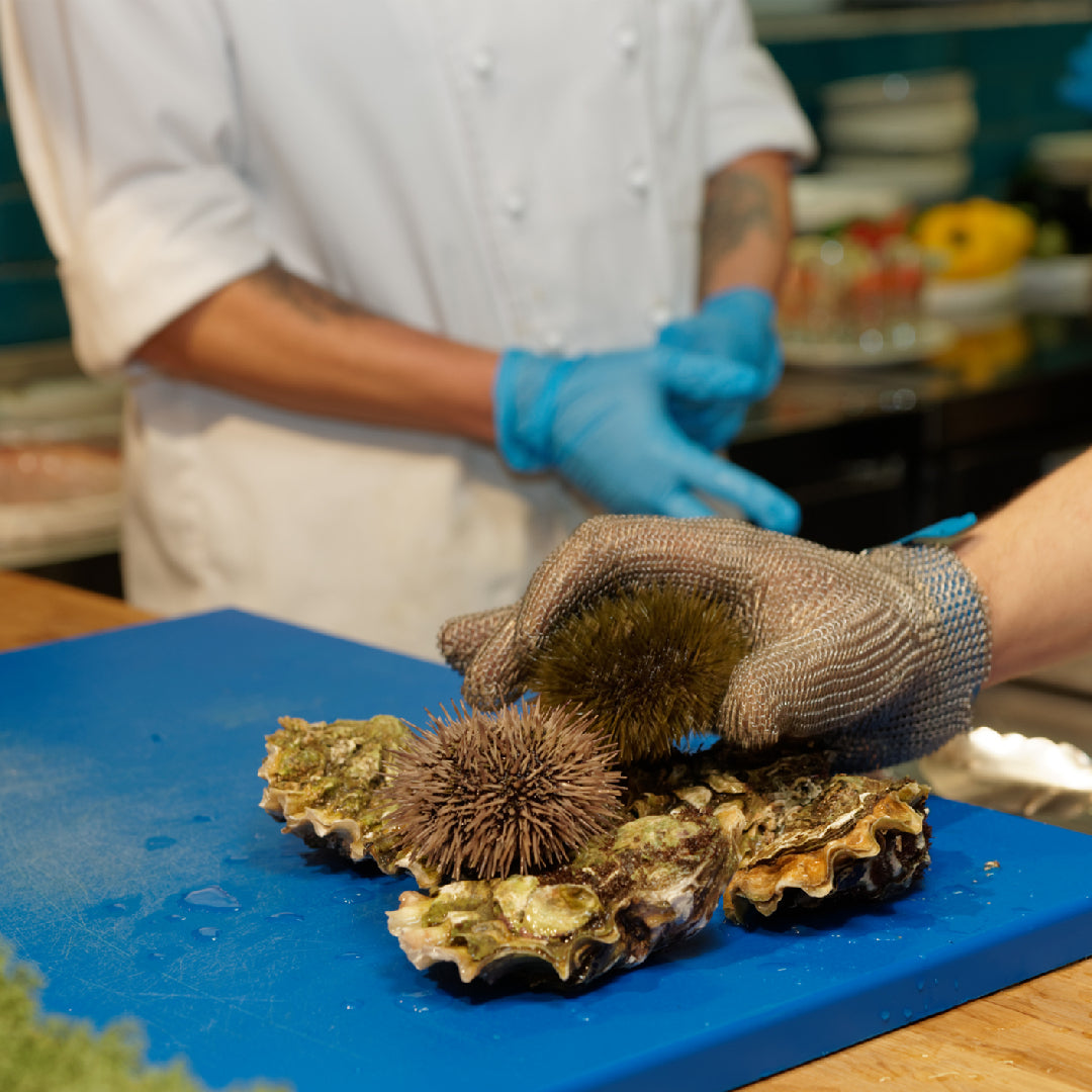 Freshly harvested sea urchin roe (uni) in a wooden tray showing vibrant golden-orange color, sourced from cold Pacific waters for sushi-grade quality