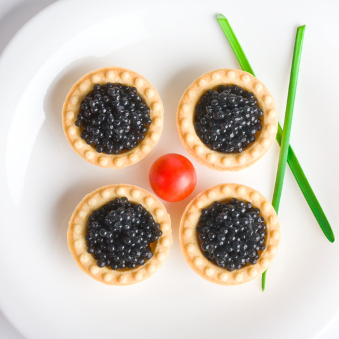 Caviar pearls served on blinis with crème fraîche alongside a glass of Champagne