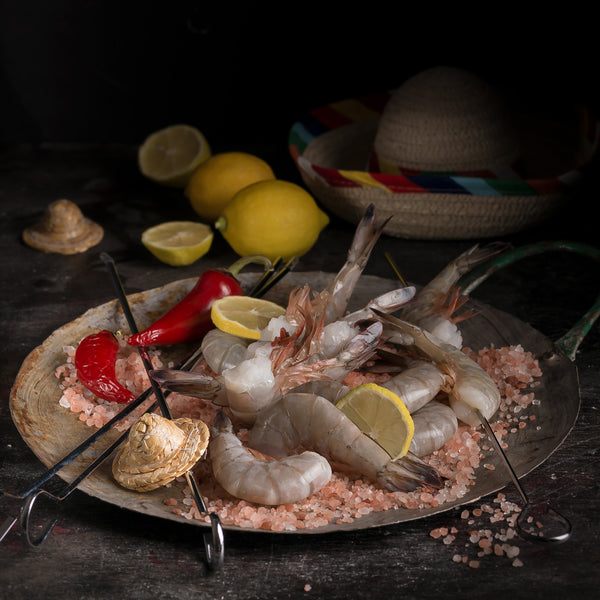 Shrimp skewers arranged on a dark plate with lemon