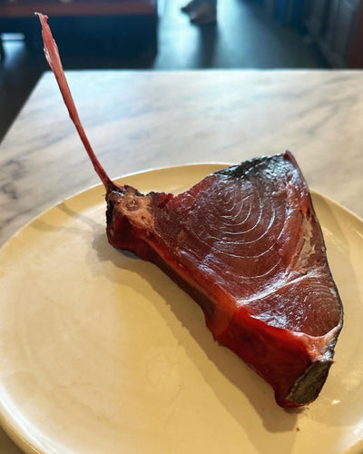 Whole dry-aged Tomahawk Tuna on a cutting board, showcasing its rich color and premium quality