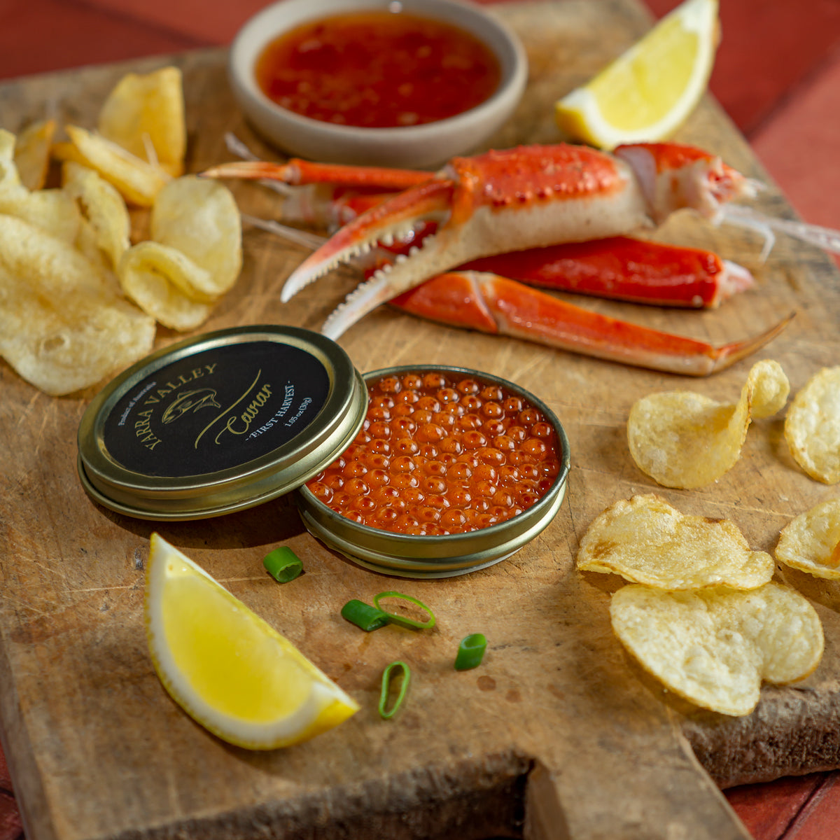 Atlantic salmon roe in an open tin on a wooden cutting board, with crab claws in the background for a gourmet seafood presentation