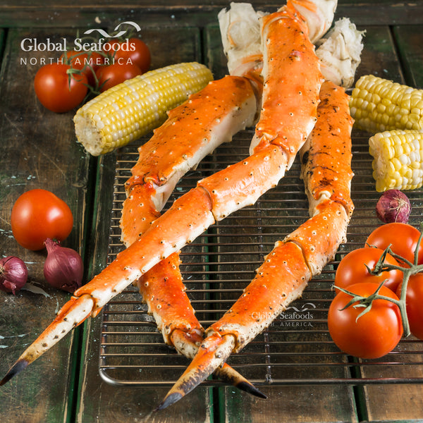 Ready-to-eat King Crab legs displayed with fresh corn and sliced lemons on a rustic wooden surface, showcasing generous size and vibrant color
