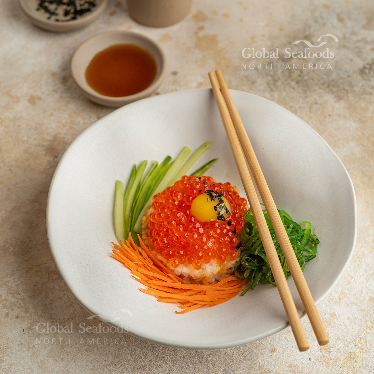 Japanese-style rice bowl topped with Coho salmon red caviar and nori, served with chopsticks for a traditional seafood dish presentation
