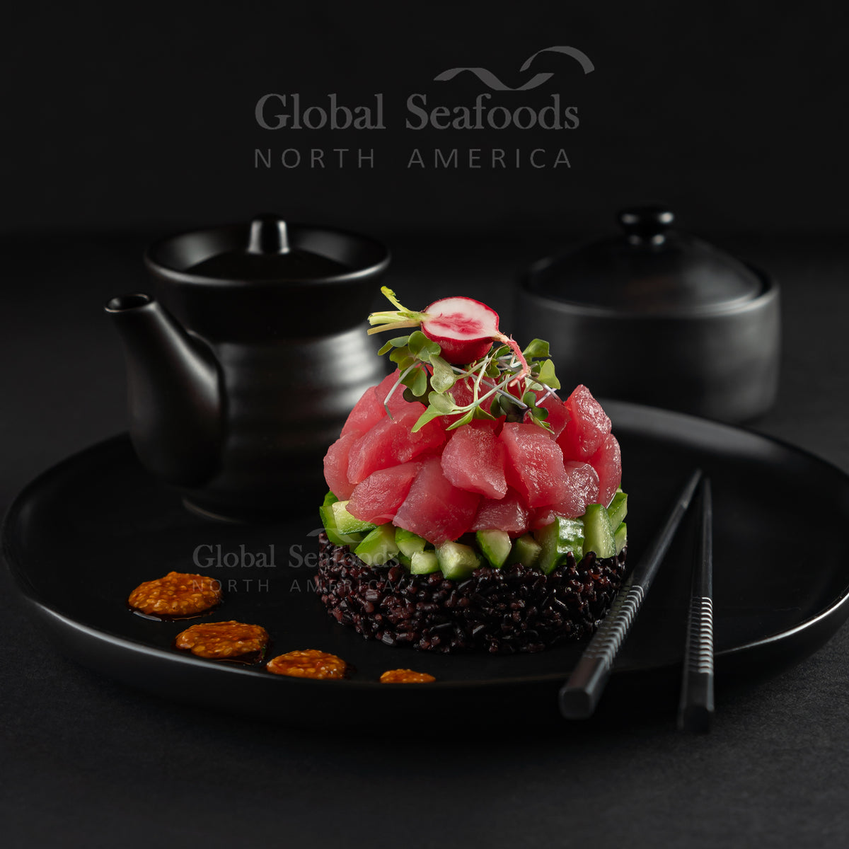 Tuna poke over cucumber and black rice on a black plate