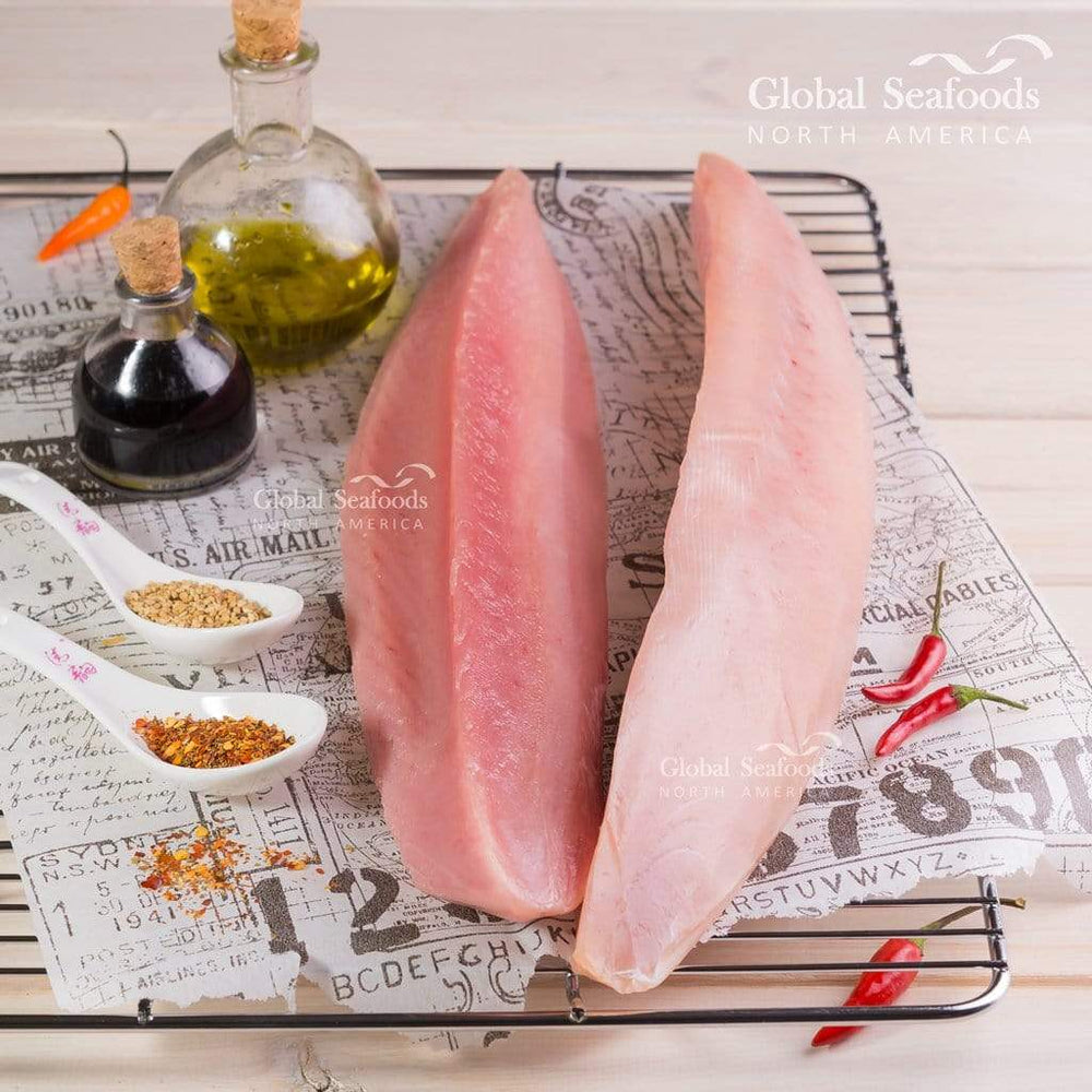 Fresh albacore tuna fillets laid out on a table, light pink flesh with smooth texture, ready for cooking
