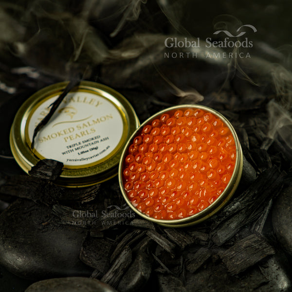 Open tin of smoked salmon roe with its labeled lid on charred wood with wisps of smoke