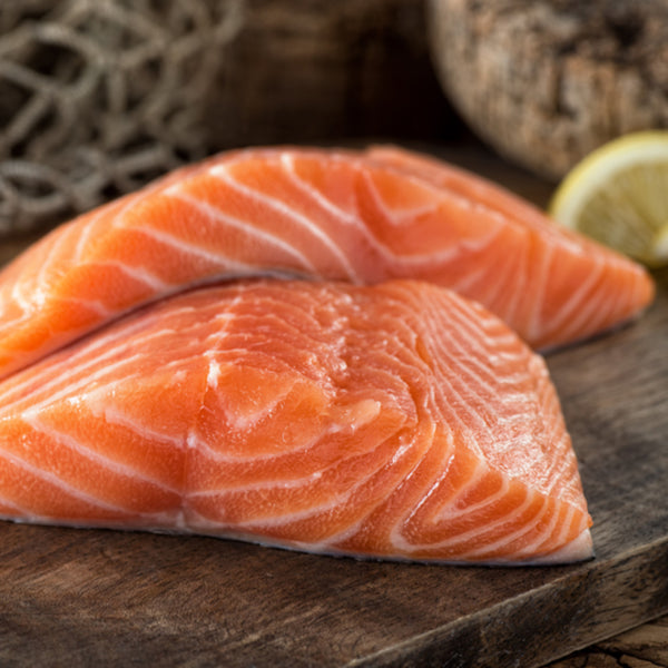 Two Atlantic salmon portions on a wooden surface