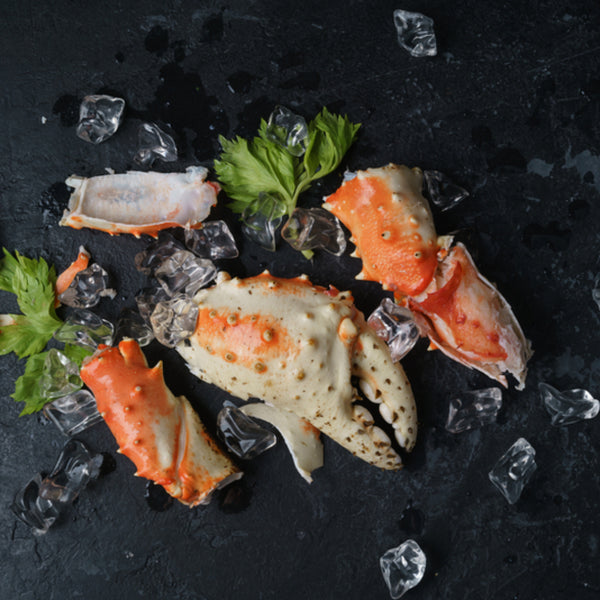 King crab leg pieces served on a black crockery platter, highlighting their rich color and meaty texture