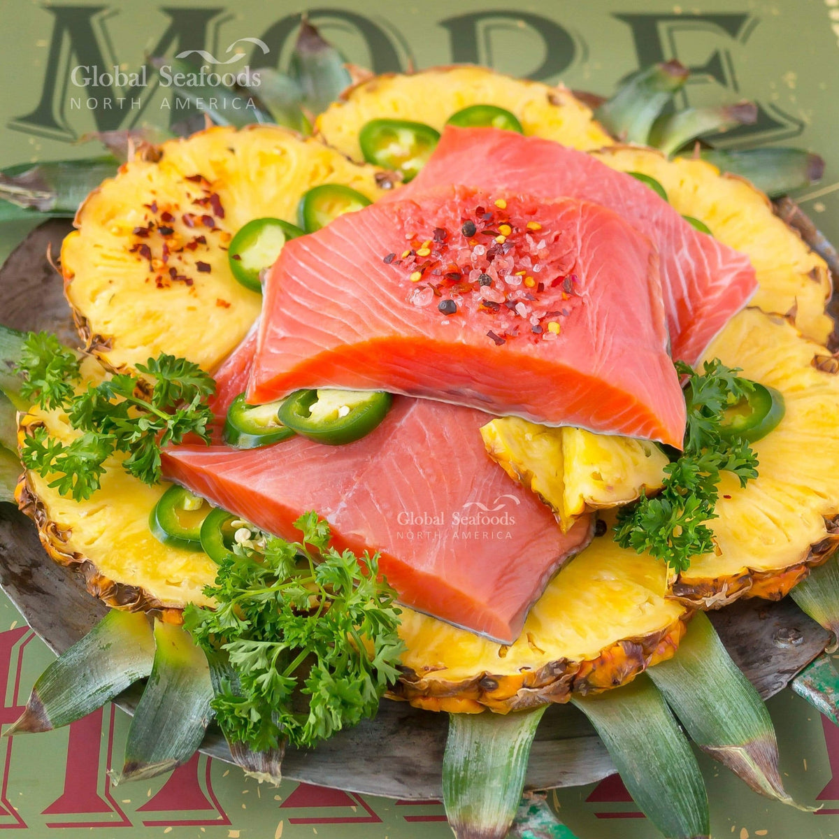 Three skin-on king salmon portions on pineapple slices with green chili