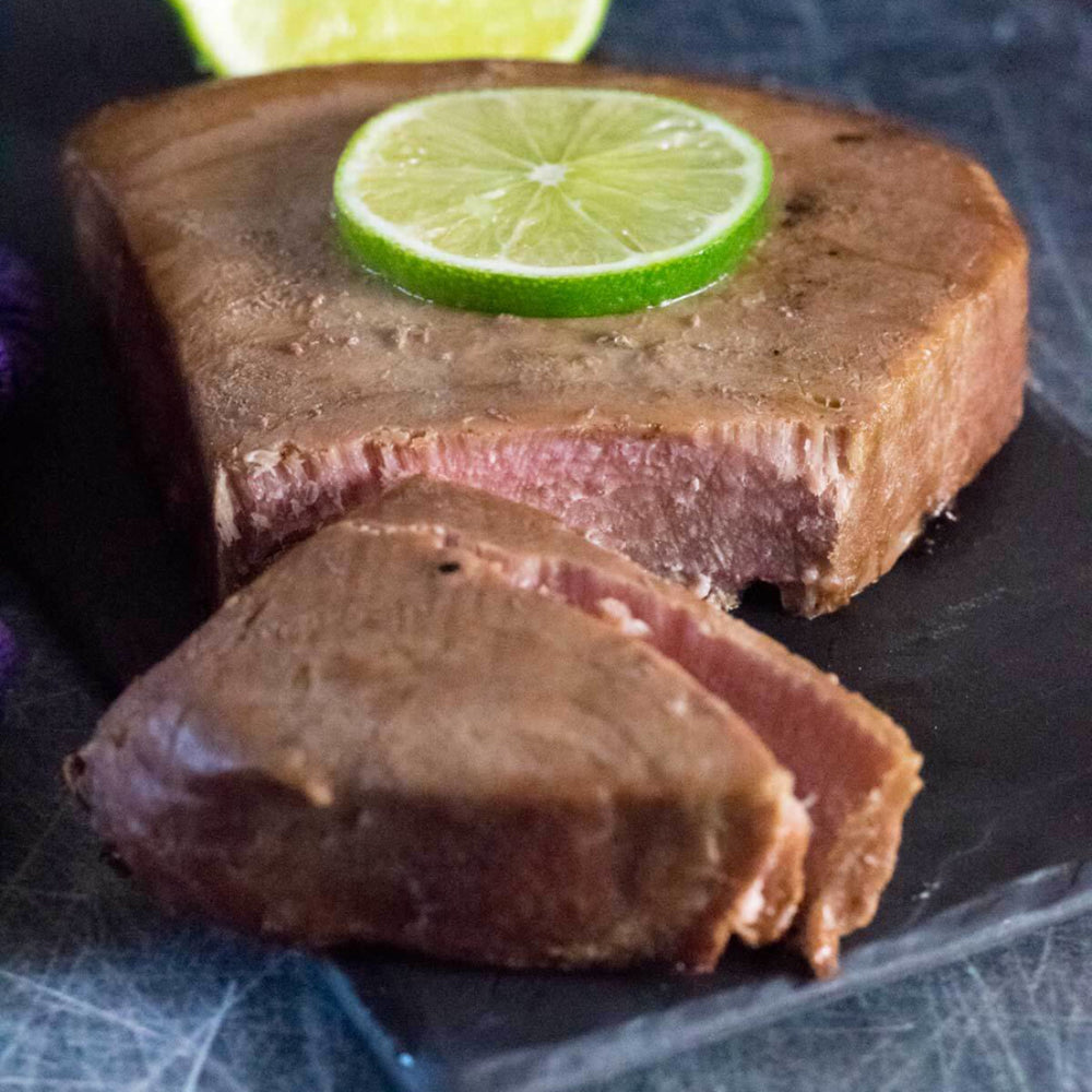 Smoked ahi tuna steak with a fresh lime slice on top, showcasing deep color and rich texture for gourmet seafood presentation
