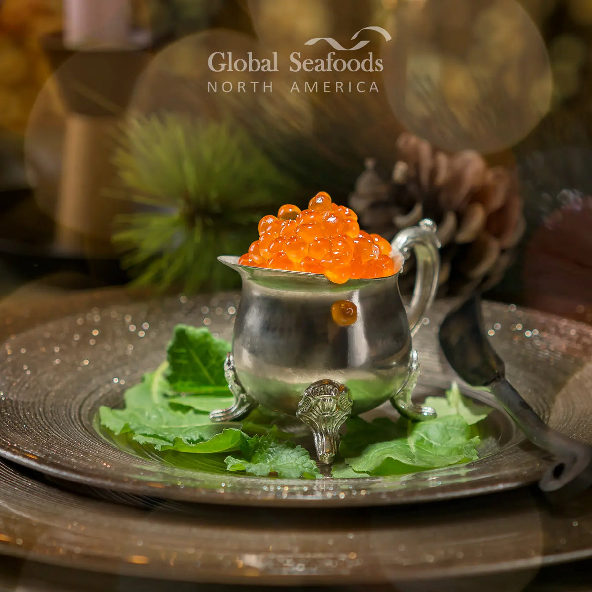 Chum salmon caviar in a small silver-colored pitcher on a plate with leafy greens