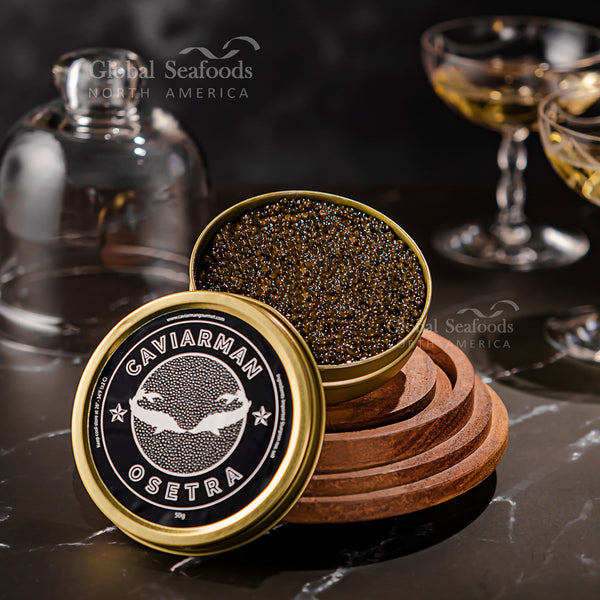 Open tin of Russian Osetra caviar on wooden stands, with a Caviarman lid, glass decanter and coupe glasses