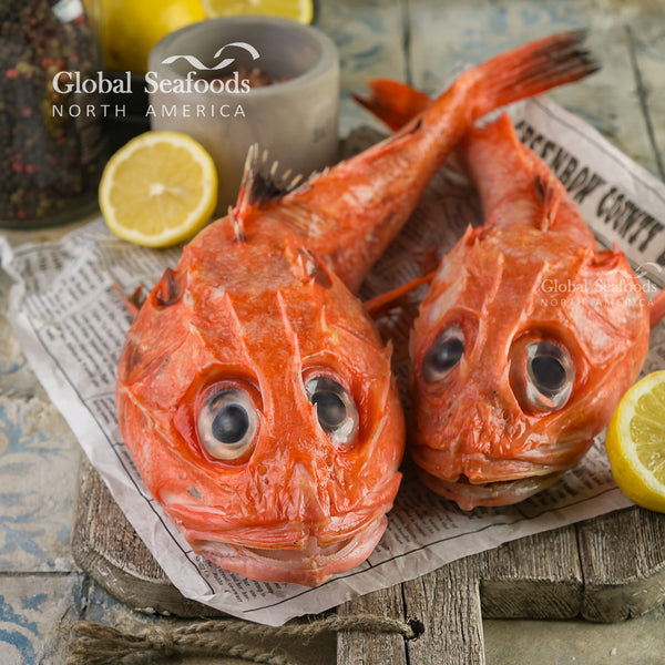 Two whole kinki rockfish on newspaper and a wooden board
