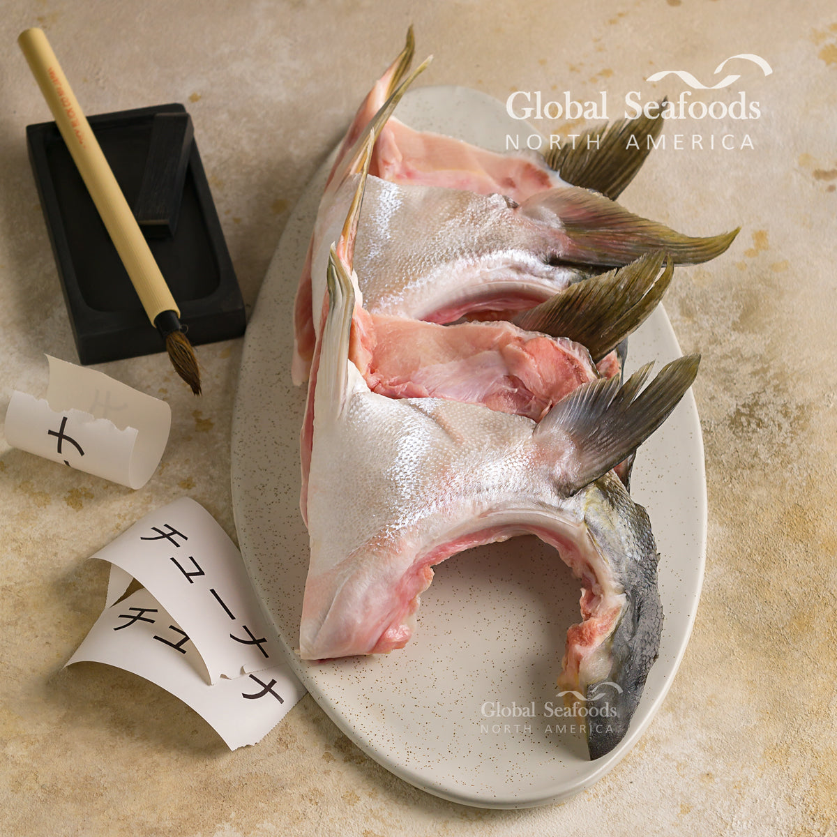 Hamachi (yellowtail) collars on an oval plate beside chopsticks